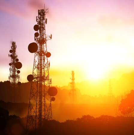 Communications towers silhouetted against a sunset